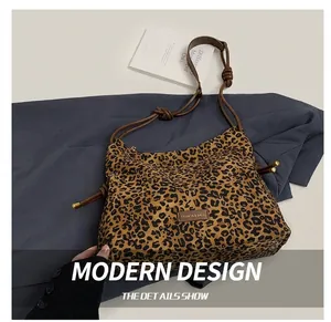 Detail of leopard print tote bag with leather straps and fashion label on canvas surface
