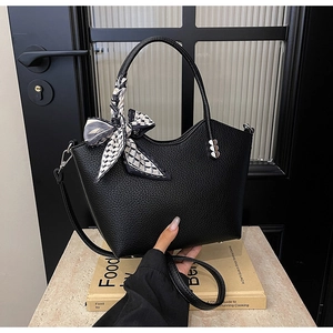 Détail du sac seau noir en cuir avec foulard en soie au manche et boucle cœur argentée