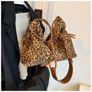 Close-up of leopard print tote bag with brown leather straps and gold drawstring hardware