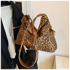 Detail of leopard print tote bag featuring a brown knot strap and gold metal accents