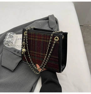 Detail der rot-grünen Karo-Schultertasche mit Goldkette und Anhänger auf einem Blazer