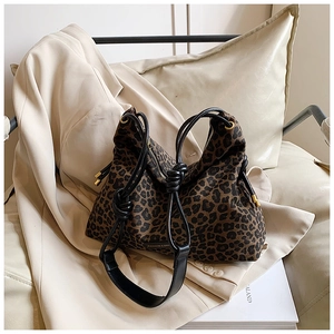 Close-up of leopard print canvas tote bag with black leather straps and fashion label