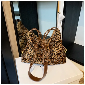 Close-up of leopard print tote bag with brown leather knotted handles and gold accents