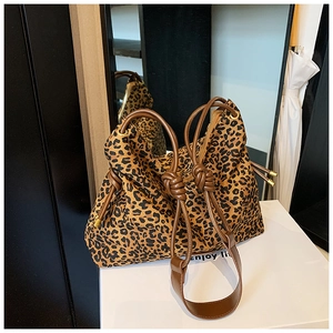 Detail of leopard print tote bag with brown knotted shoulder strap and gold hardware