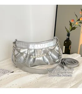 Détail du sac argenté motif crocodile avec chaîne de perles et charms en forme de cœur