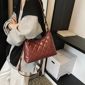 Burgundy quilted hobo bag with gold chain strap and key pendant shown on shoulder