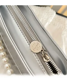 Détail du sac en cuir argenté avec fermeture éclair métallique et décorations perlées