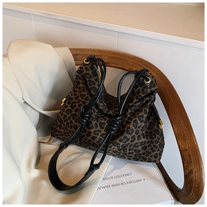 Detail of leopard print tote bag featuring black knotted straps and gold metal eyelets