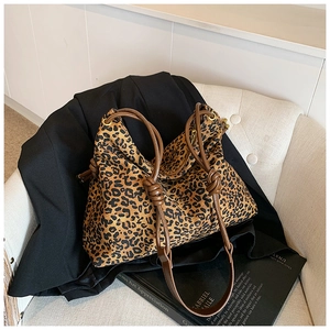 Detail of leopard print tote bag with brown knotted shoulder strap on white chair