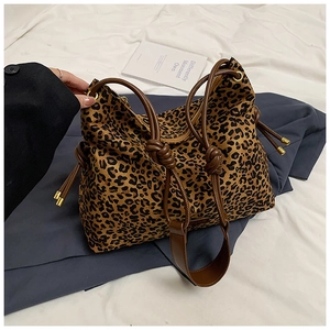 Detail of leopard print tote bag with brown leather straps and drawstring side