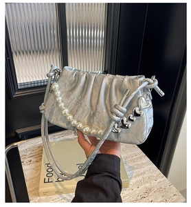 Detail of silver pleated cloud bag featuring pearl handle and heart-shaped metal charms