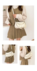Detailed close-up of cream shoulder bag with pearl chain, crocodile texture and pleats