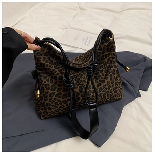 Detail of leopard print canvas tote bag featuring black leather straps and gold hardware
