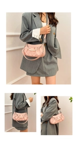 Detailed view of pink pleated underarm bag with pearl strap and heart charm accents