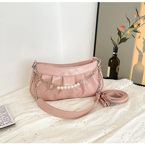 Detail of pink croc-embossed underarm bag with pearl heart chain and pleat design