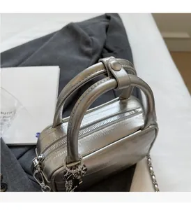 Detail of silver metallic handbag with sturdy handles and chain strap on grey fabric