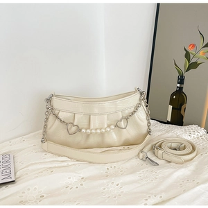 Detail of cream white pleated bag with crocodile pattern and pearl heart chain charms