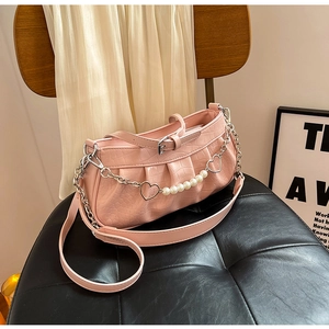 Detailed view of pink croc-embossed leather bag with pearl chain and heart pendant