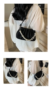 Detail of black pleated shoulder bag with elegant pearl strand and silver heart chain