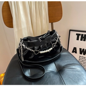 Close-up of black crocodile pattern pleated bag with pearl chain and heart charm