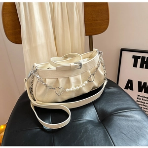 Detail of crocodile embossed cream white shoulder bag with pearl heart chain and pleated design