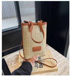 Detail of a straw and leather crossbody phone bag with short handle and strap