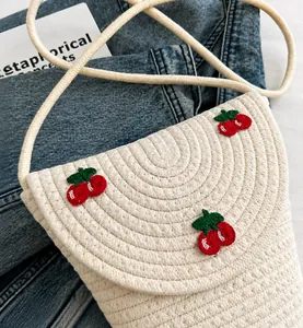 Detail einer beigen kleinen Strohtasche mit roter Kirschstickerei und Seilriemen