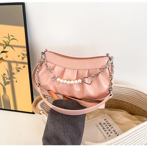 Detailed macro of pink crocodile pattern leather bag with pearl and heart chain charm