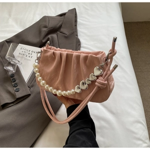 Detail of pink pleated cloud bag featuring pearl strap and heart pendant charms