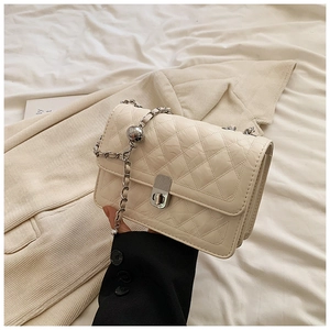 Detail of quilted beige crossbody bag with silver ball chain and metal clasp