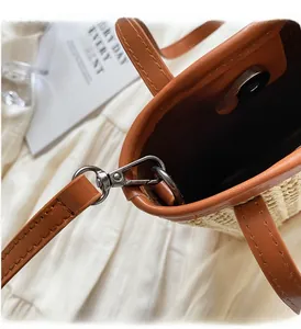 Detail of straw bag with orange leather strap, gunmetal hardware and magnetic snap closure