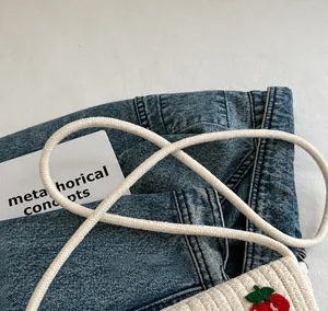 Detail eines weißen Seilschultergurts an Kinder-Strohtasche mit Erdbeer-Stickerei