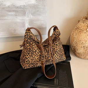 Fashionable leopard print tote bag with brown knotted shoulder straps on black suit jacket