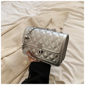 Detail of silver quilted leather bag with metallic chain strap and adjustable ball buckle