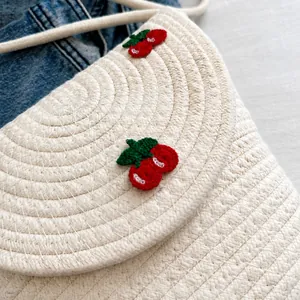 Detailansicht der cremefarbenen Strohtasche mit roter Kirschstickerei und Baumwollgewebe