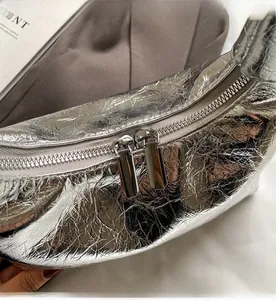 Detail of a silver crescent bag featuring dual smooth metal zippers and crinkled texture