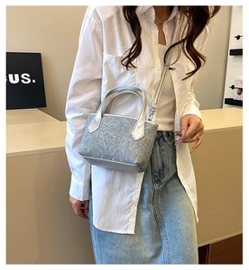 Détail d'un mini cabas plissé bleu à texture marbrée, porté par un mannequin femme