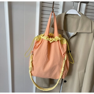 Dettaglio borsa a secchiello bicolore in nylon con chiusura a coulisse e tracolla