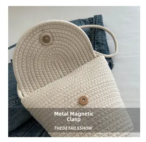 Dettaglio della chiusura magnetica in metallo su una borsa a tracolla intrecciata color crema