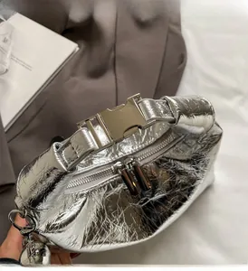 Detail of silver metallic handbag with crinkled texture, sturdy handle and metal buckle