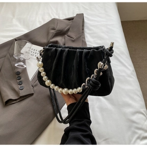 Detail of black pleated cloud bag with large pearl handle and silver heart buckle