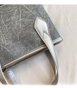 Détail de la poignée en cuir argenté et du motif marbre sur un sac à main gris