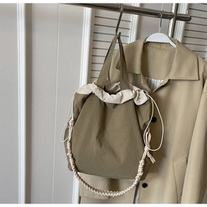 Dettaglio della borsa a secchiello in nylon verde con coulisse e manico intrecciato