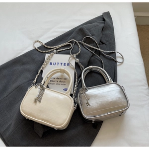 Detail showing cross-textured leather on cream and silver chain bags with key charm
