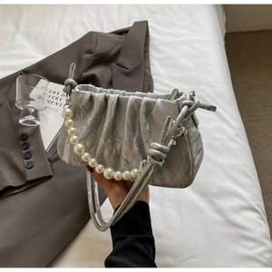 Detail of silver pleated handbag featuring elegant pearl handle and knotted leather strap