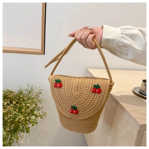 Dettaglio di una mini borsa a secchiello in paglia con ricamo a ciliegia e manico