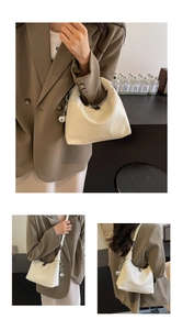 Detail view of cream dumpling bag with silver charm and adjustable crossbody strap