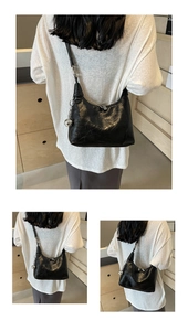 Three-way view of a black pleated shoulder bag with silver orb charm on a model