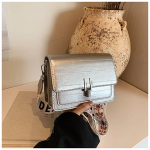 Detail of silver crossbody bag with decorative wide strap featuring floral embroidery