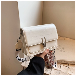 Close-up of white crocodile pattern square bag with silver clasp and floral strap